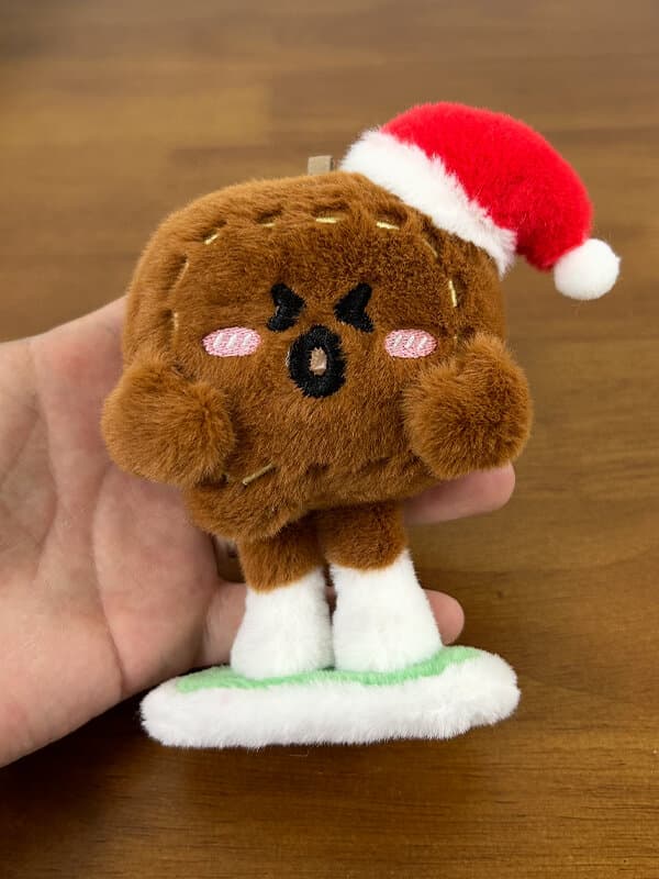 빨간 산타 모자, 자수 X-눈, 핑크 볼, 아이싱 디테일의 갈색 진저브레드 캐릭터 — 선전 공방 크리스마스 F&B 봉제인형