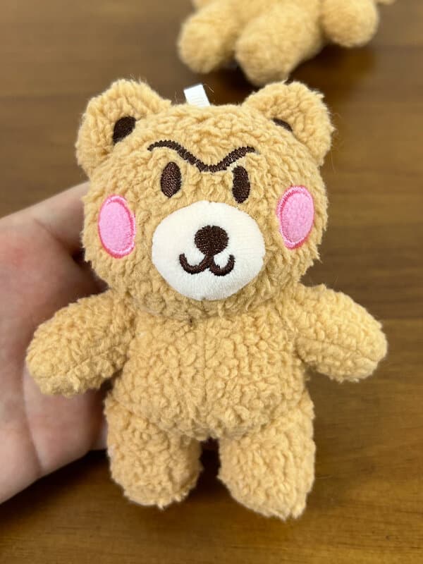 굵은 자수 눈썹, 핑크 볼, 흰 주둥이, 시그니처 심술 얼굴의 갈색 테디베어 — 선전 공방 캐릭터 브랜드 봉제인형